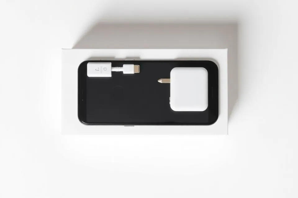 Illustrative flat lay of a smartphone box with cable, charger and SIM pin